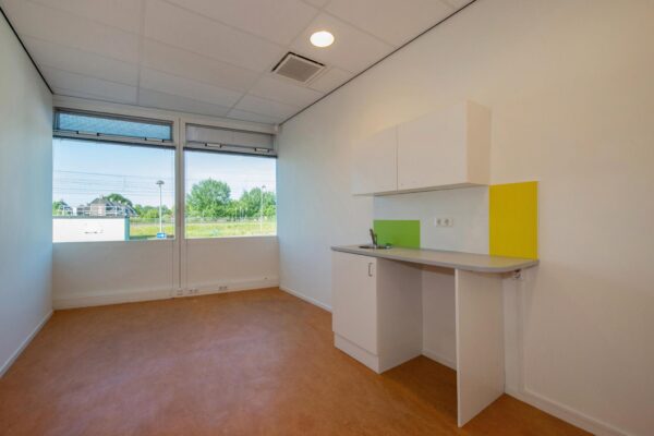 Klein, licht studio-appartement aan de Harriet Freezerhof met twee ramen en een eenvoudige kitchenette.